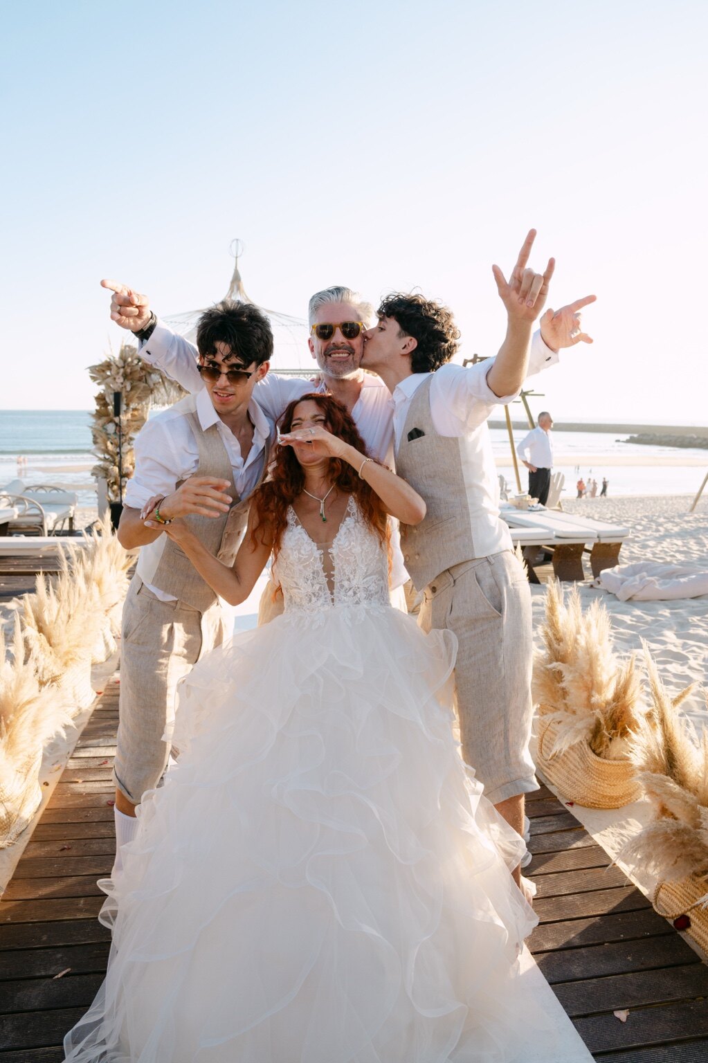 A noiva celebra descontraidamente com a família junto à praia.