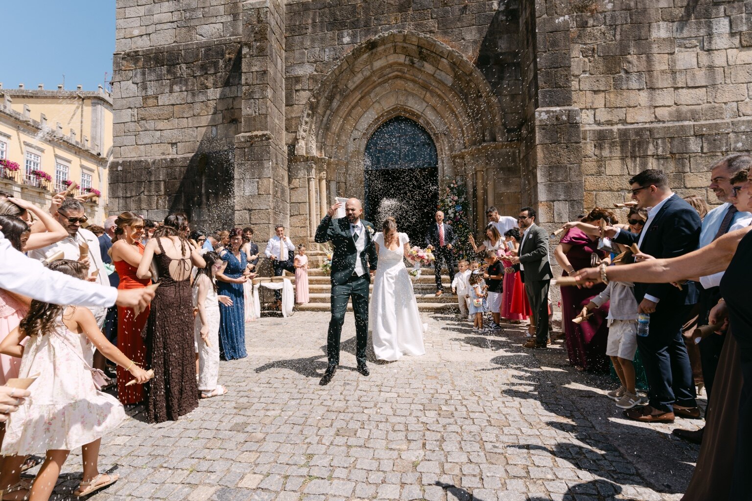 Os noivos saem da igreja entre duas filas de convidados e pétalas.
