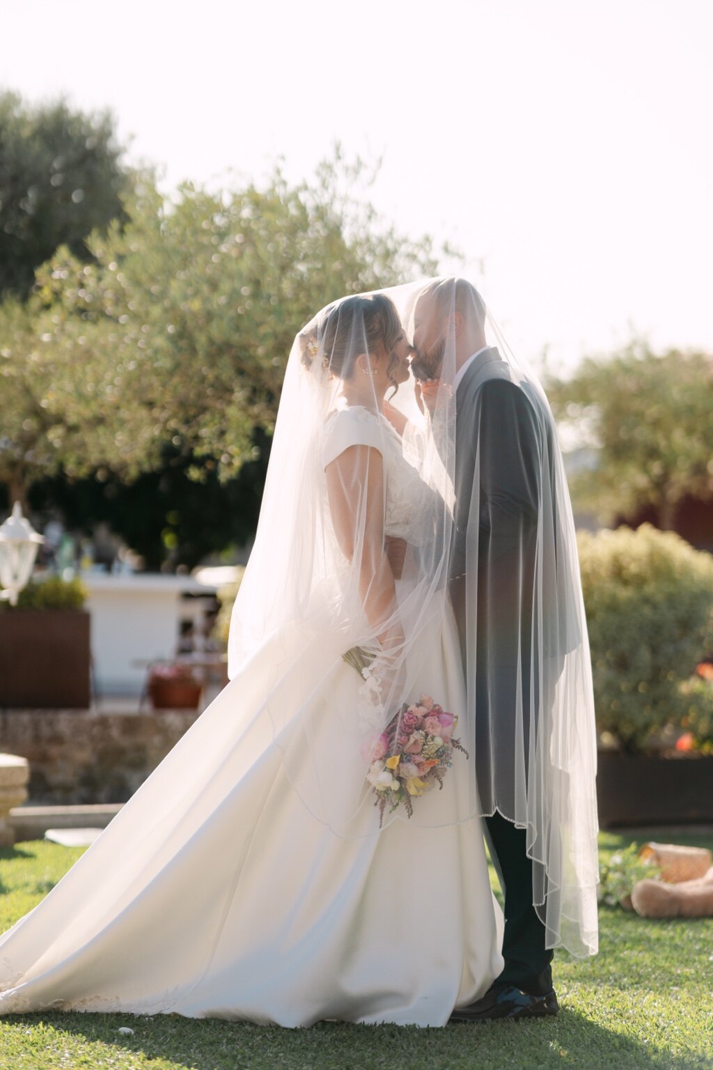 Os noivos encontram-se sob o véu num retrato suave ao ar livre.
